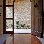 porte entrée taillée sur mesure verre et bois délimitation sol parquet mur pierres